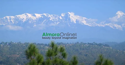 Snow-covered Himalayan peaks above green wooded hills